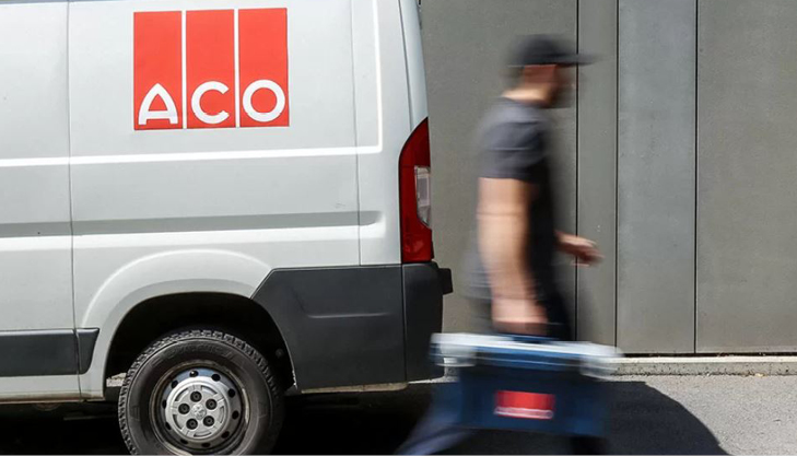 ACO-Transporter vor einer grauen Wand, daneben eine Person mit Werkzeugkoffer.