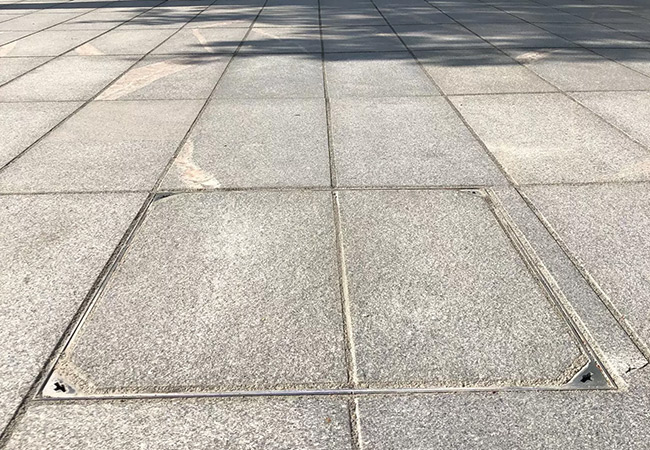 Durchgängige Pflasterfläche mit Schachtabdeckung in Fußgängerzone