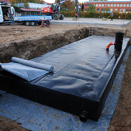 Blockrigolen mit einer Abdichtungsbahn umhüllt in einer Baugrube mit Erdreich.