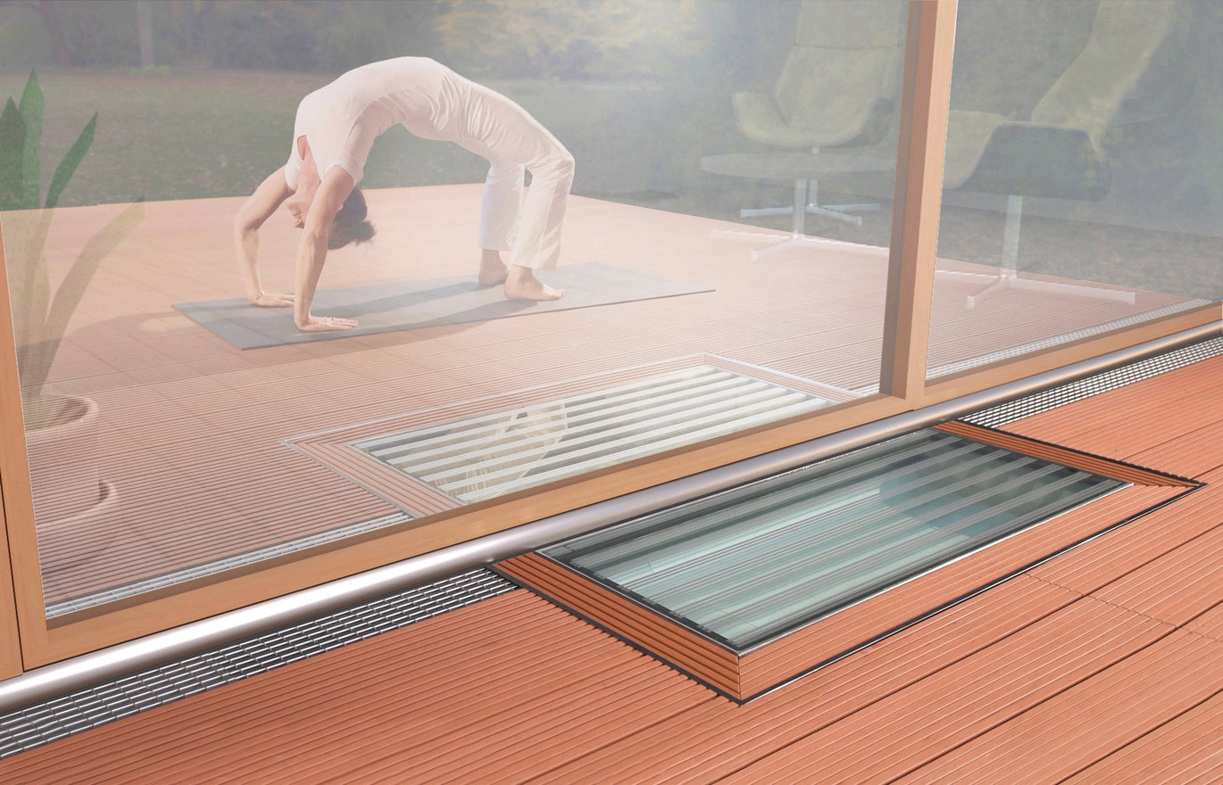 Terrassenfront mit eingelassenem Lichtschacht im Holzdeck, im Innenraum Person beim Rückwärtsbogen auf Yogamatte.