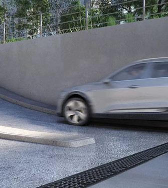 Auto verlässt eine Tiefgarage über eine Rampenauffahrt nach oben, unten in der Auffahrt befindet sich eine Entwässerungsrinne.