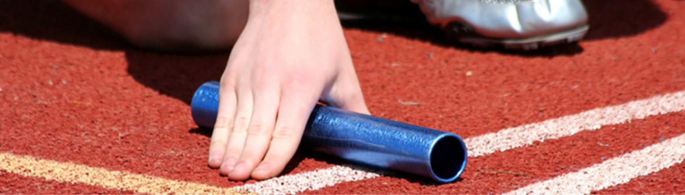 Staffellauf Hand umfasst einen Staffelstab auf einer Tartanbahn.
