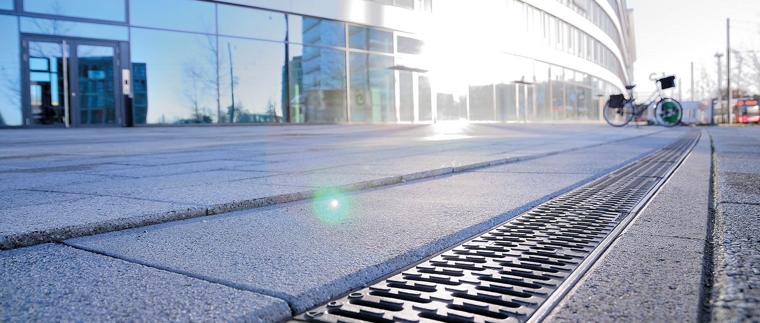 Entwässerungsrinne vor modernem Gebäude in der Sonne