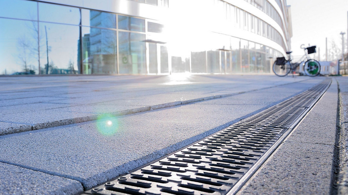 Entwässerungsrinne vor modernem Gebäude in der Sonne