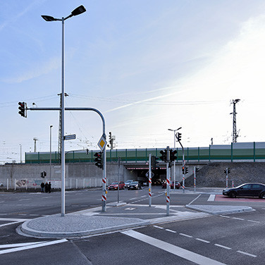 Stehende Autos vor Ampeln an einer Straßenkreuzung mit einem Tunnel im Hintergrund.