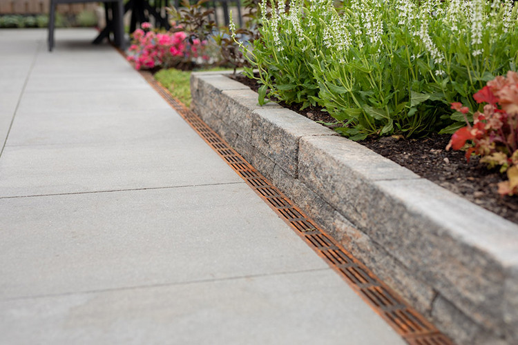 Terrasse mit kleiner Palisade und eloxierter Entwässerungsrinne.