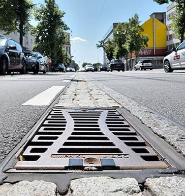 Straße mit rechteckiger Schachtabdeckung und Autos am Straßenrand