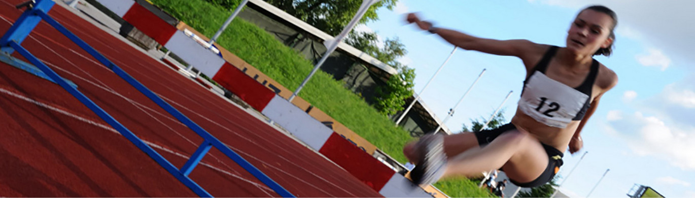 Hürdenlauf Frau beim Hürdenlauf auf einer Tartanbahn.