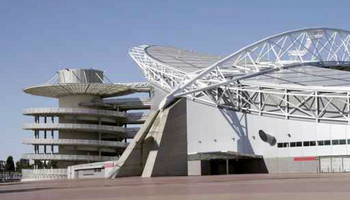 Außenansicht des Olympiastadions in Sydney, mit seiner modernen und geschwungenen Architektur. Das Stadion hat eine ovale Form und ist von einem weitläufigen, offenen Dach bedeckt. Die Fassade ist schlicht und funktional.