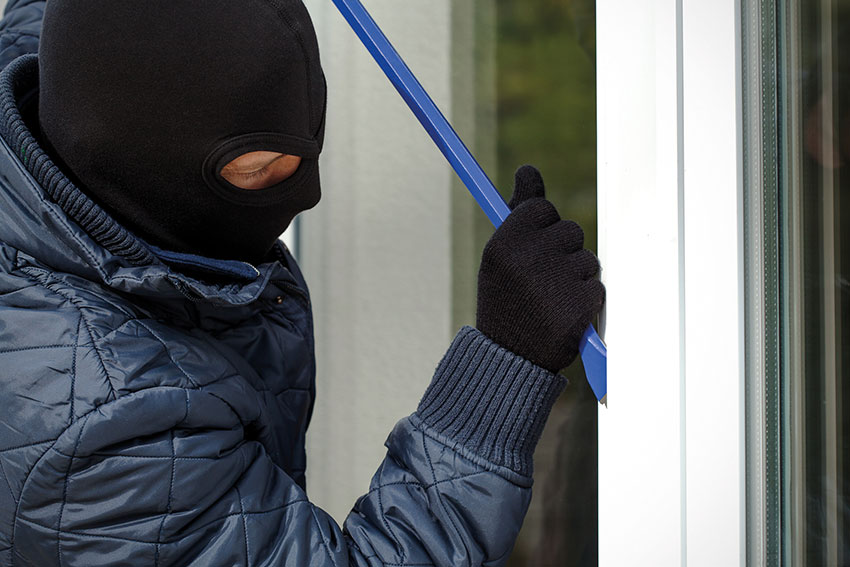 Einbrecher mit Brecheisen am Fenster