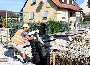 Bauarbeiter beim Einsetzen des Straßenablaufs in der Weißenburger Straße, Röttenbach