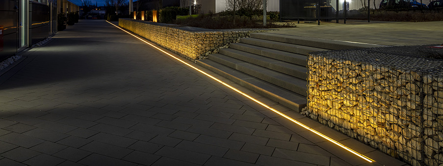 Dezent beleuchtet: Treppenstufen und Steinmauer mit der ACO Sideline – eine Kombination aus Entwässerungsrinne ACO Multiline Seal in und der Lichtlinie OGL1 von Instalighting.