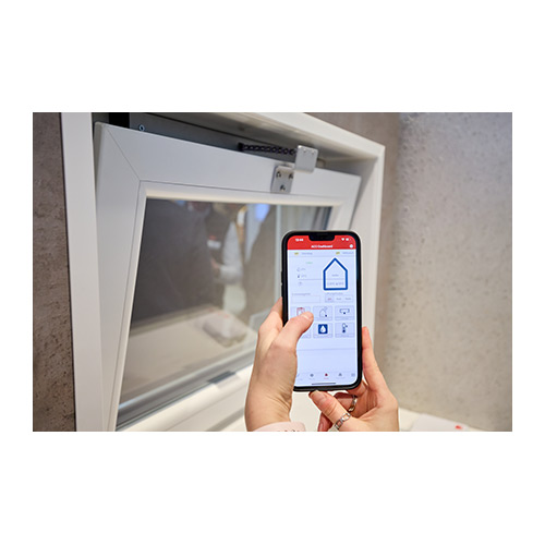 Leicht geöffnetes Kellerfenster, davor Hände mit Smartphone und App.